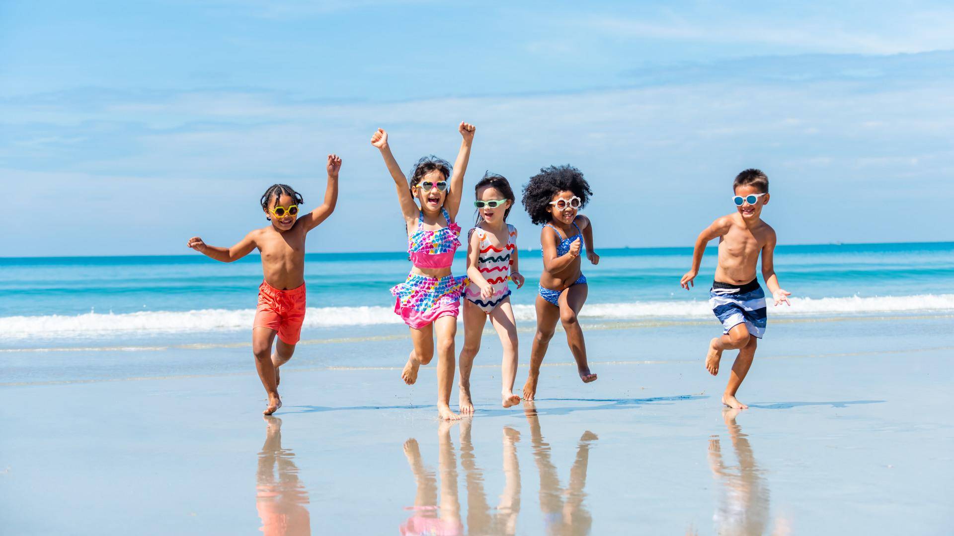 Gruppo di bambini che corrono sul bagnasciuga